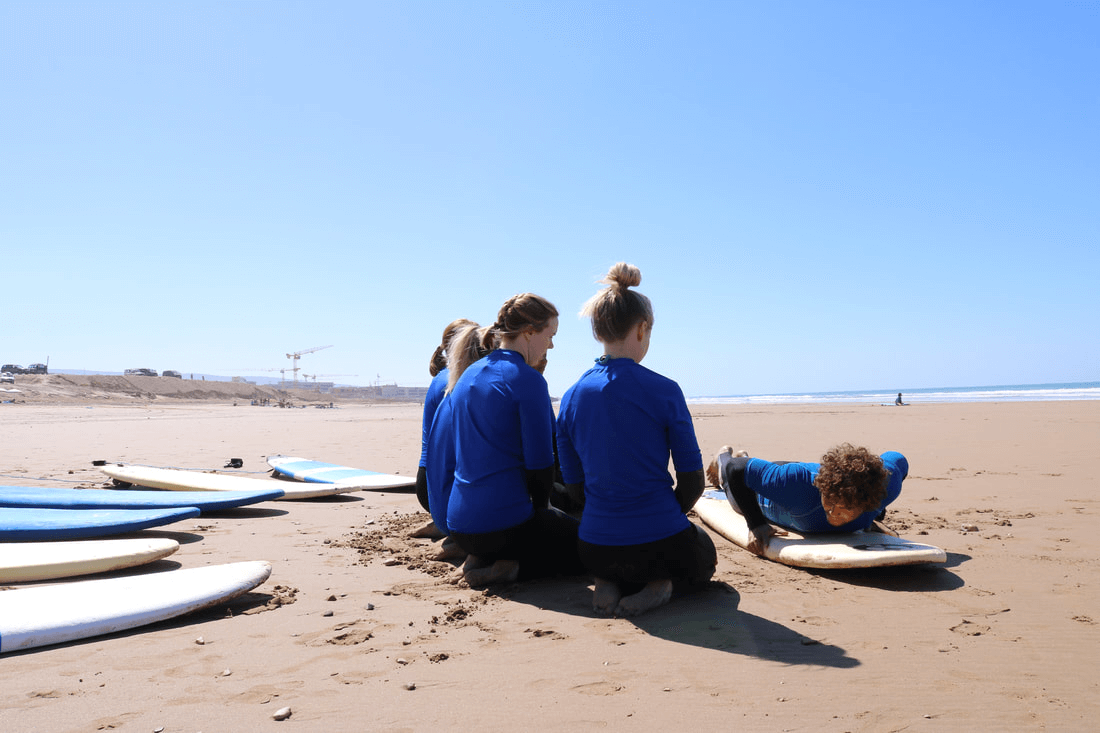 Beginner surfers learn to surf on the beach in Taghazout